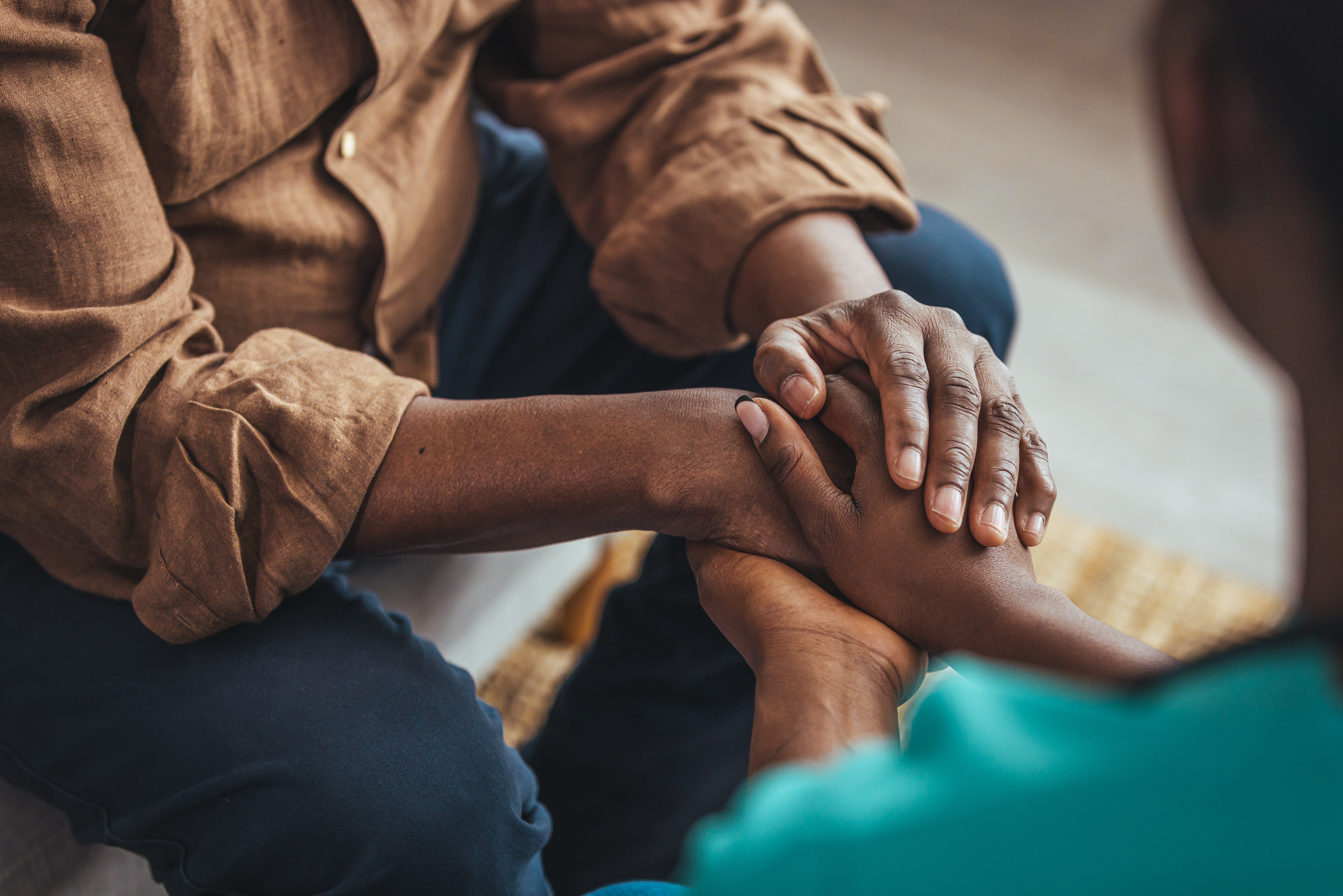 A closeup of a man and a woman's hands clasped together in support